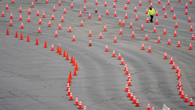 A worker arranges cones at a mostly-empty vaccination site at Dodger Stadium, Los Angeles, Feb. 11, 2021.