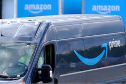 In this file photo, an Amazon Prime logo appears on the side of a delivery van as it departs an Amazon Warehouse location in Dedham, Mass.