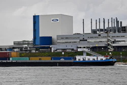 In this file photo, a container ship passes the Ford car plant in Cologne, Germany.