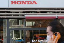 A woman wearing a face mask walks in front of a Honda Motor Co. showroom in Tokyo.