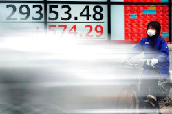 A woman wearing a protective mask rides a bicycle in front of an electronic stock board showing Japan's Nikkei 225 index at a securities firm Monday, Feb. 8, 2021, in Tokyo. Asian shares mostly rose Monday, tracking a rally on Wall Street last week, with Japan's benchmark momentarily reaching three-decade highs, on growing optimism about the global economy.