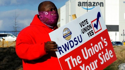 Michael Foster of the Retail, Wholesale and Department Store Union holds a sign outside an Amazon facility where labor is trying to organize workers on Tuesday, Feb. 9, 2021. President Joe Biden said workers in Alabama and across the country have the right to join a union without intimidation from their companies. His comments come as Amazon workers in the state are voting on whether they should unionize. In a two minute video posted to Twitter, Biden didn’t mention Amazon by name, or say how workers should vote.