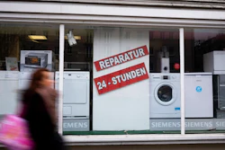 A person walks past a shop offering the repair of electronic equipment and domestic appliances in Berlin, Germany, Friday, Feb. 26, 2021. Companies that sell refrigerators, washers, hairdryers or TVs in the European Union will need to ensure those appliances can be repaired for up to 10 years. The new 'right to repair' comes into force across the 27-nation bloc Monday, March 1, 2021. The posters read: ' Repair - 24 hours'.