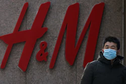 A man wearing a face mask walks by a Swedish fashion brand H&M store outlet in Beijing.