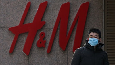 A man wearing a face mask walks by a Swedish fashion brand H&M store outlet in Beijing.