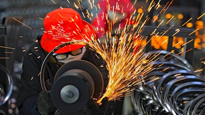 Workers wearing face masks polish bicycle wheel rims at a factory in Hangzhou in east China's Zhejiang province on Feb. 19, 2021. China's manufacturing recovery weakened for a third month in February as exports and new orders declined, according to two surveys released on Monday, March 1, 2021.