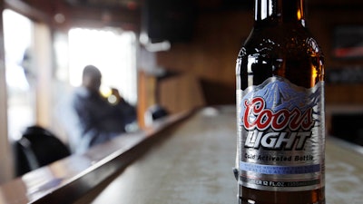 In this file photo, a bottle of Coors Light sits on the bar as a patron sips a beer at a tavern.