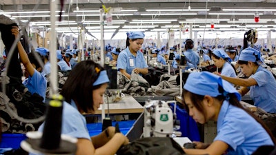 In this Sept. 29, 2015, file photo, workers in the Great Forever factory stitch clothes in the Hlaing Tharyar industrial zone outside Yangon, Myanmar. Garment workers in Myanmar are urging major international brands to denounce the recent military coup there and put more pressure on factories to protect workers from being fired or harassed - or worse arrested and killed for participating in protests.
