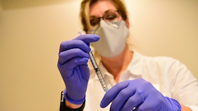 This file photo provided by Johnson & Johnson shows a pharmacist preparing to give an experimental COVID-19 vaccine.