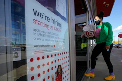In this file photo, a passerby walks past a hiring sign while entering a Target store in Westwood, MA.