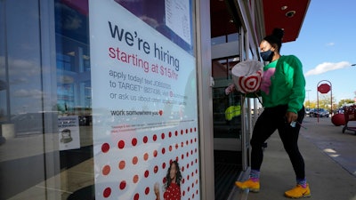 In this file photo, a passerby walks past a hiring sign while entering a Target store in Westwood, MA.