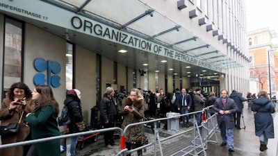 In this file photo taken before the coronavirus pandemic restrictions, people stand outside the headquarters of the Organization of the Petroleum Exporting Countries, OPEC, in Vienna, Austria.