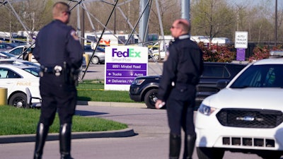 Police stand near the scene where multiple people were shot at the FedEx Ground facility early Friday morning in Indianapolis.