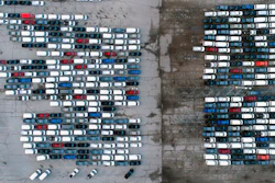 In this aerial photo, mid-sized pickup trucks and full-size vans are seen in a parking lot outside a General Motors assembly plant where they are produced Wednesday, March 24, 2021, in Wentzville, Mo. The global shortage of semiconductors is forcing General Motors to further cut production at six North American factories as chip supplies seem to be growing tighter. The shutdowns likely will crimp dealer inventory of vehicles made at the plants, but GM says it has managed to keep factories humming that make hot-selling and profitable full-size pickup trucks and SUVs.
