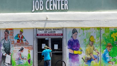 In this May 7, 2020, file photo, a person looks inside the closed doors of the Pasadena Community Job Center in Pasadena, Calif., during the coronavirus outbreak. While most Americans have weathered the pandemic financially, about 38 million say they are worse off now than before the outbreak began in the U.S. According to a new poll from Impact Genome and The Associated Press-NORC Center for Public Affairs Research 55% of Americans say their financial circumstances are about the same now as a year ago, and 30% say their finances have improved.