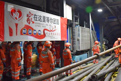 In this photo released by Xinhua News Agency, rescue workers stand near a banner which reads: 'Home is waiting for your region' at the entrance to a flooded coal mine.
