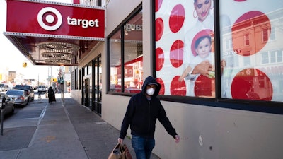 In this April 6, 2020 file photo, a customer wearing a mask carries his purchases as he leaves a Target store during the coronavirus pandemic, in the Brooklyn borough of New York. Target says it will spend a a total of more than $2 billion at Black-owned businesses by 2025 as part of its effort to advance racial equity. As part of its program, the Minneapolis-based discounter will add products from more than 500 Black-owned businesses across all types of merchandising areas.