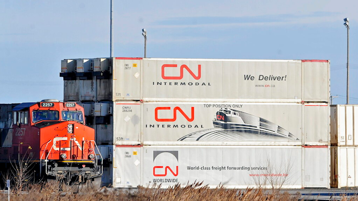 In this May 13 photo, a Canadian National locomotive passes by freight containers at the Canadian National Taschereau yard in Montreal.