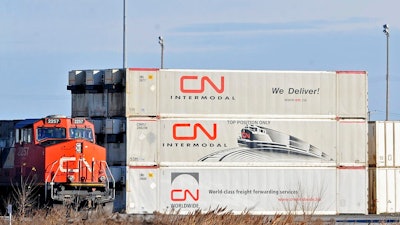 A Canadian National locomotive passes by freight containers at the Canadian National Taschereau yard in Montreal, Saturday, Nov. 28, 2009. Canadian National sweetened its offer to buy Kansas City Southern railroad Thursday, May 13, 2021, and derailed rival Canadian Pacific’s bid for the railroad that handles traffic in the United States and Mexico.