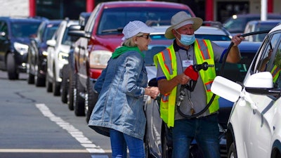 A customer helps pumping gas at Costco, as other wait in line, on Tuesday, May 11, 2021, in Charlotte, N.C. Colonial Pipeline, which delivers about 45% of the fuel consumed on the East Coast, halted operations last week after revealing a cyberattack that it said had affected some of its systems.