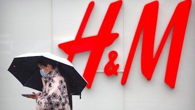 A woman walks by an H&M clothing store at a shopping mall in Beijing on March 26, 2021. An American business group warned Tuesday, May 11, 2021 that government-instigated consumer boycotts of foreign shoe, clothing and other brands in China are making companies less willing to invest. Brands including Swedish retailer H&M, Adidas and Nike have been targeted by demands online for consumer boycotts. That came after state media criticized them for expressing concern about reports of possible forced labor by ethnic minorities in the Xinjiang region of China's northwest.
