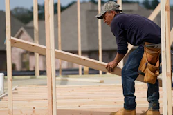 A carpenter aligns a beam for a wall frame at a new house site in Madison County, Mississippi.