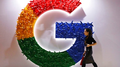 A woman walks past the logo for Google at the China International Import Expo in Shanghai, Nov. 5, 2018.