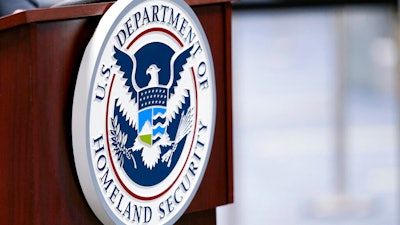In this Nov. 20, 2020 photo, a U.S. Department of Homeland Security plaque is displayed a podium as international passengers arrive at Miami international Airport where they are screened by U.S. Customs and Border Protection in Miami.
