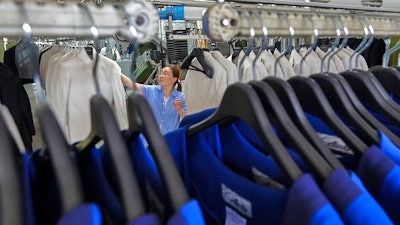 A worker arranges the business suits at Shandong Daiyin Textile and Garment Group factory in Tai'an in east China's Shandong province on Saturday, May 29, 2021. China's manufacturing held steady in May, a survey showed Monday, adding to signs a post-pandemic rebound is leveling off.