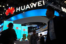 In this Oct. 31, 2019, file photo, attendees walk past a display for 5G services from Chinese technology firm Huawei at the PT Expo in Beijing. U.S. President Joe Biden has nearly doubled the list of Chinese companies whose shares are off-limits to U.S. investors in the latest sign he is not softening Washington's stance toward Beijing. Telecoms equipment maker Huawei Technologies, China’s big state-owned telecoms companies and China National Offshore Oil Corp. are on the new list of 59 companies.