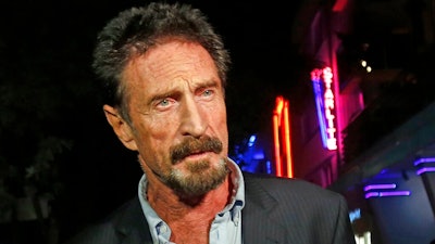 In this Dec. 12, 2012, file photo, anti-virus software founder John McAfee answers questions to reporters as he walks on Ocean Drive, in the South Beach area of Miami Beach, Fla. McAfee, the outlandish security software pioneer who tried to live life as a hedonistic outsider while running from a host of legal troubles, was found dead in his jail cell near Barcelona, Spain, on Wednesday, June 23, 2021. His death came just hours after a Spanish court announced that it had approved his extradition to the United States to face tax charges punishable by decades in prison, authorities said.