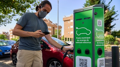 A man charges his electric car at an electrical charging point in Rivas Vaciamadrid, Spain, Tuesday, June 15, 2021. Spain is Europe's second-leading car maker but it is lagging behind when it comes to electric cars, a situation that the government aims to change by using around five billion euros of the EU pandemic recovery funds to kickstart the electric car industry.