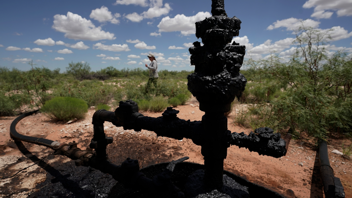 Ashley Williams Watt walks near a wellhead and flowline at her ranch near Crane, Texas, July 9, 2021.