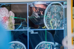 Neurosurgeon Dr. Edward Chang is reflected in a computer monitor displaying brain scans as he performs surgery at the University of California-San Francisco in 2017.