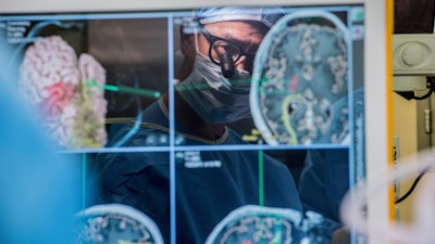 Neurosurgeon Dr. Edward Chang is reflected in a computer monitor displaying brain scans as he performs surgery at the University of California-San Francisco in 2017.