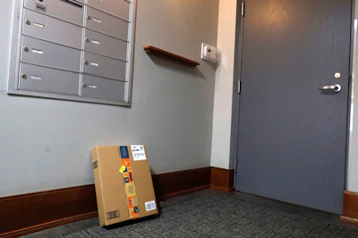 An Amazon package sits by the mailbox at Jason Goldberg's apartment, Monday, March 29, 2021, in Chicago. Amazon is making a push to install a device on buzzer systems in apartment buildings throughout the country that allows its delivery drivers to whip out a phone, tap a button and unlock a building's front doors whenever they need to leave packages in the lobby instead of the street.