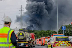 Emergency vehicles near an access road to the Chempark, over which a dark cloud of smoke is rising, Leverkusen, Germany, July 27, 2021.