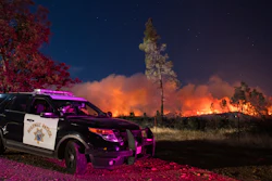 In this Sept. 28. 2020, file photo, a California Highway Patrol officer watches flames visible from the Zogg Fire near Igo, Calif. Pacific Gas & Electric is facing criminal charges because its equipment sparked the wildfire that killed four people and destroyed hundreds of homes, a Northern California prosecutor announced Thursday, July 29, 2021.