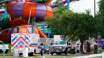 Emergency personnel vehicles are parked near the scene where people are being treated after chemical leak at Six Flags Hurricane Harbor Splashtown.
