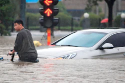 A man rides a bicycle through a flooded intersection in Zhengzhou in central China's Henan Province, Tuesday, July 20, 2021. China's military has blasted a dam to release floodwaters threatening one of its most heavily populated provinces.