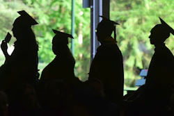 In this Friday, June 1, 2018,, file photo, graduates are silhouetted against the green landscape as they line up to receive their diplomas at Berkshire Community College's commencement exercises at the Shed at Tanglewood in Lenox, Mass. Critics of traditional four-year degree programs say grads leave burdened with student loans and no clear path to a career. But experts say the four-year degree is still a good investment since it leads to higher overall lifetime earnings compared to workers without a degree.