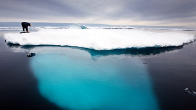 In this file photo dated July 2007, an Inuit seal hunter touches a dead seal atop a melting iceberg near Ammassalik Island, Greenland. The left-leaning government on Greenland which could be sitting on vast amounts of oil, has decided to suspend all oil exploration.