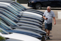 In this Sunday, June 14, 2020, photograph, a prospective buyer looks over a long row of unsold 2020 CX-5 sports-utility vehicles sedans sits at a Mazda dealership in Littleton, Colo.