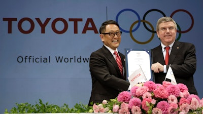 In this March 13, 2015 file photo, Toyota President and CEO Akio Toyoda, left, and IOC President Thomas Bach pose with a signed document during a press conference in Tokyo as Toyota signed on as a worldwide Olympic sponsor in a landmark deal.