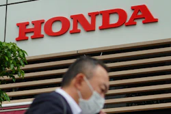 A man wearing a protective mask to help curb the spread of the coronavirus walks past the logo of Honda Motor Company in Tokyo, May 13, 2021.