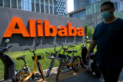 A man wearing a face mask walks past the offices of Chinese e-commerce firm Alibaba in Beijing, Tuesday, Aug. 10, 2021. China's largest e-commerce company, Alibaba, says it has fired a manager accused of sexually assaulting a female employee during a business trip.