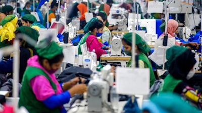 Garment employees work in a sewing section of the Snowtex Outerwear Ltd. factory in Savar, Bangladesh, on Aug. 9, 2021. Bangladesh is suffering through its deadliest surge of the pandemic, but you wouldn't know it looking at its factories, markets and malls. At the Snowtex Outerwear Ltd. factory on the outskirts of Dhaka, the company's 15,000 workers now walk through a “disinfectant tunnel” in which they are sprayed with sanitizer before they get to work turning heaps of fabric into clothing sold in countries around the world.