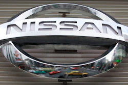 In this Feb. 8, 2012, file photo, vehicles are reflected on the logo of the Nissan Motors Co. at a showroom in Tokyo's Ginza shopping district. Nissan says its huge factory in Smyrna, Tennessee, will close for two weeks starting Monday, Aug. 16, 2021 due to computer chip shortages brought on by a coronavirus outbreak in Malaysia.