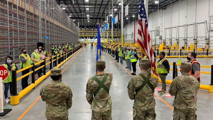 The North Dakota State University Color Guard leads associates through the Fargo Amazon Fulfillment Center's opening ceremony.