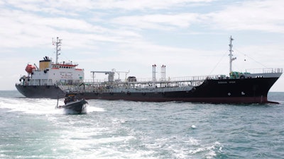 In this undated photo released by Indonesian Navy, a navy boat sails past Panamanian-flagged tanker MT Zodiac Star anchored in Riau Island waters, Indonesia. Indonesian navy seized the massive tanker believed to be loaded with thousands of tons of wasted black oil and has brought the ship to shore for further investigation, officials said Thursday, Sept. 2, 2021.